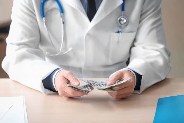 Doctor with money at table. Corruption concept — Stock Photo, Image