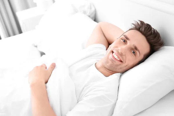 Young man lying on white pillow at home — Stock Photo, Image