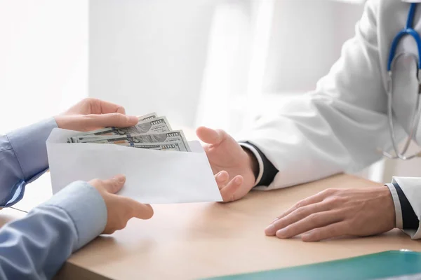 Doctor recibiendo dinero de un hombre en la mesa. Concepto de corrupción —  Fotos de Stock