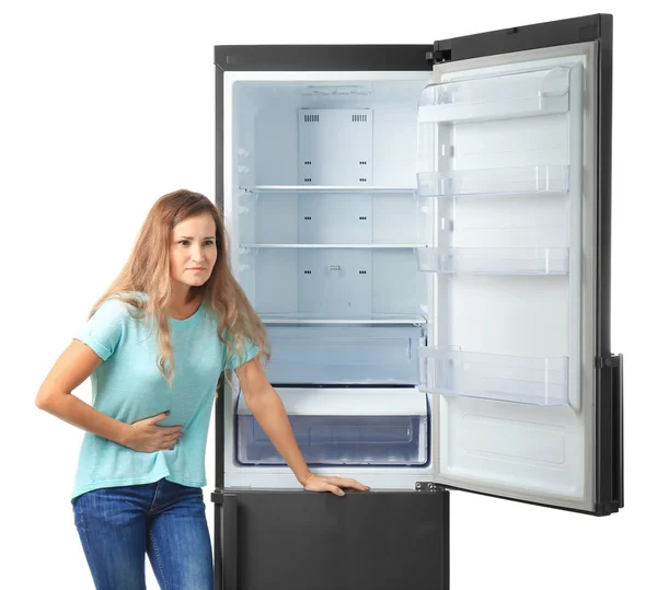 Donna affamata vicino frigorifero vuoto su sfondo bianco — Foto Stock