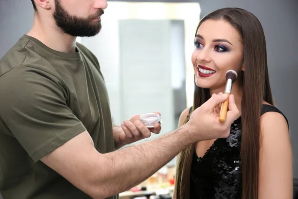 Professionell makeupartist arbetar med attraktiv ung kvinna inomhus — Stockfoto