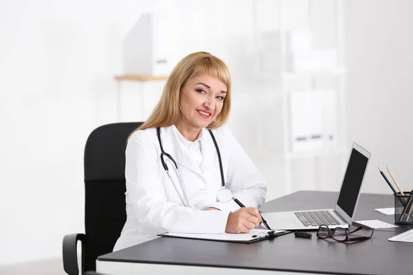 Médica preenchendo formulário de inscrição no consultório — Fotografia de Stock