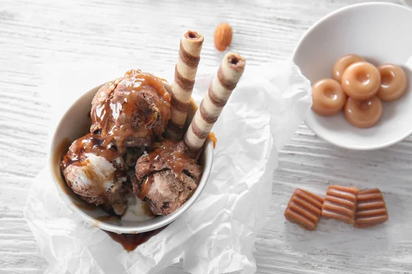 Cuenco con helado y salsa de caramelo en la mesa — Foto de Stock