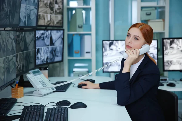Жінка охоронець розмовляє по телефону в кімнаті спостереження — стокове фото