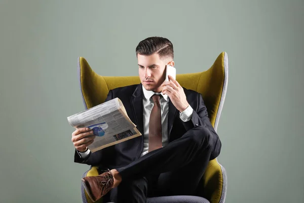 Man in elegante pak met krant op grijze achtergrond — Stockfoto