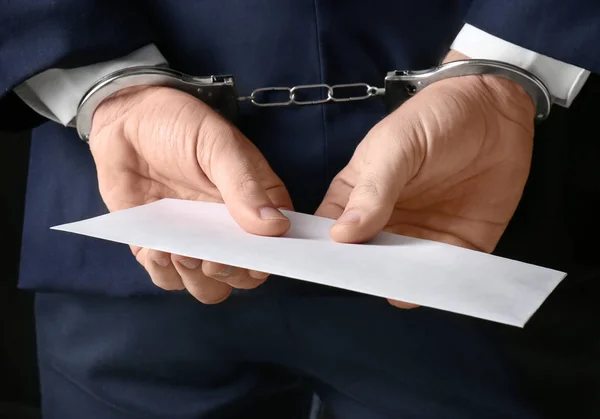 Businessman in handcuffs holding envelope with bribe, closeup — Stock Photo, Image