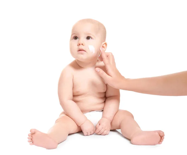 Frau cremt ihr Baby vor weißem Hintergrund ein — Stockfoto