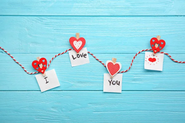 Touw met papier hartjes en zin "I love you" op houten achtergrond — Stockfoto