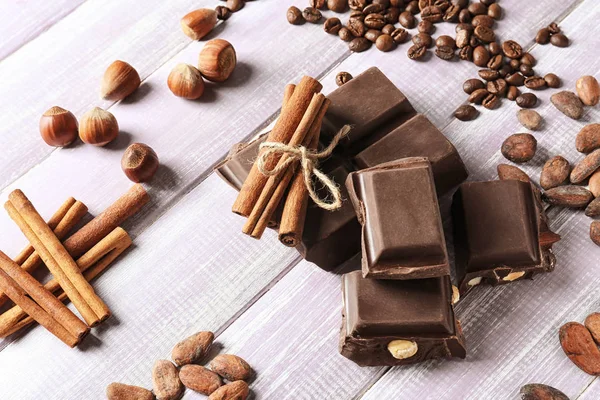 Složení s čokoláda, kakaové boby a skořice na dřevěné pozadí — Stock fotografie