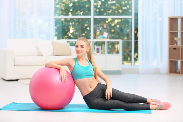 Junge Frau in Sportbekleidung mit Fitnessball drinnen — Stockfoto