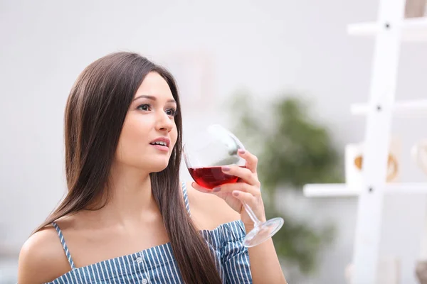 Bella giovane donna con un bicchiere di vino rilassante a casa — Foto Stock