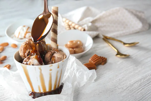 Karamellsoße in Schüssel mit Eis auf Tisch gießen — Stockfoto