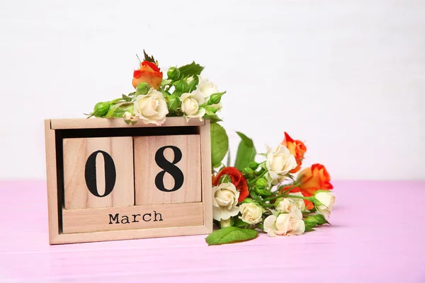 Wooden block calendar and roses on table. Composition for International Women's Day — Stock Photo, Image