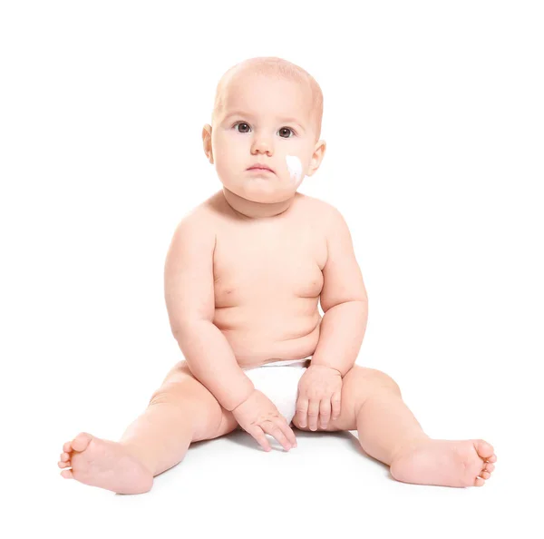 Bebê bonito com creme corporal na bochecha contra fundo branco — Fotografia de Stock