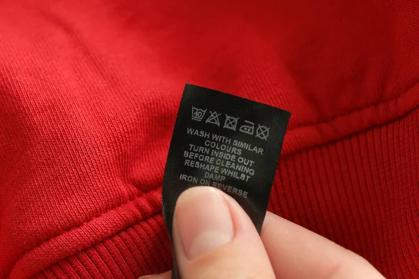 Woman reading instruction on clothing label, closeup — Stock Photo, Image