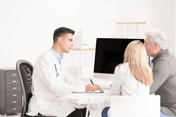 Male doctor consulting senior couple in clinic
