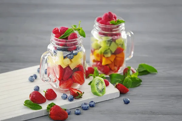 Mason jars with fruits and berries on table — Stock Photo, Image