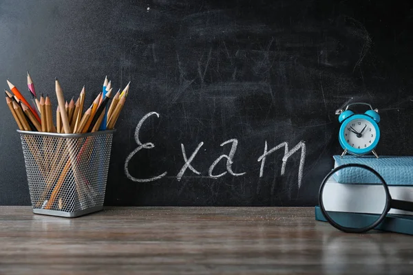 Halter mit Bleistiften, Notizbüchern und Textprüfung auf Kreidetafel geschrieben — Stockfoto