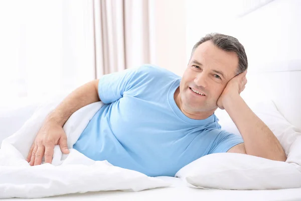 Зрелый мужчина лежит на белой подушке в помещении — стоковое фото
