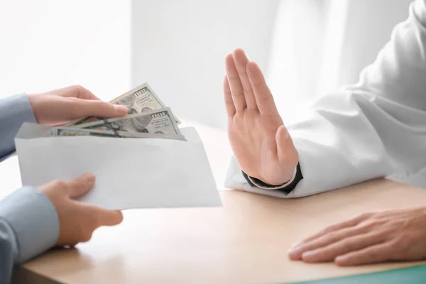 Doutor se recusando a receber dinheiro em envelope na mesa. Conceito de corrupção — Fotografia de Stock