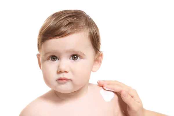 Mulher aplicando creme corporal em seu bebê contra fundo branco — Fotografia de Stock