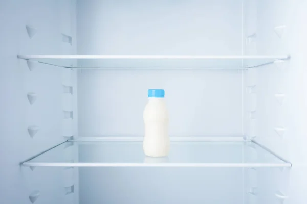 Bottle of milk in empty refrigerator — Stock Photo, Image