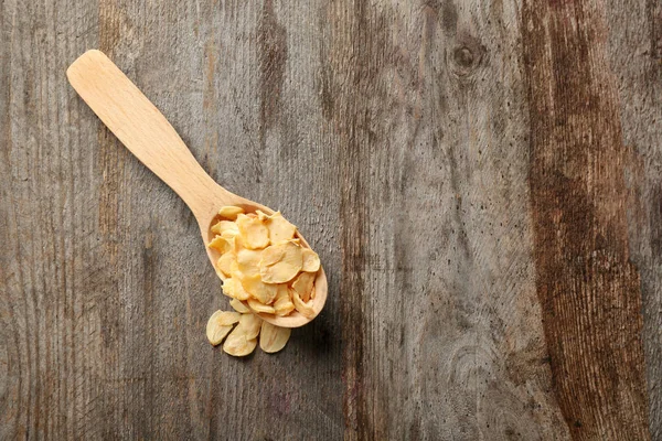 Cuchara con hojuelas de ajo secas sobre fondo de madera —  Fotos de Stock