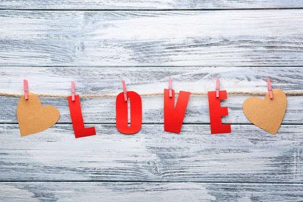 Word LOVE made of paper letters with hearts on wooden background — Stock Photo, Image