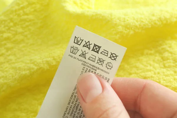 Kobieta czyta instrukcję na etykiecie ubrania, zbliżenie — Zdjęcie stockowe