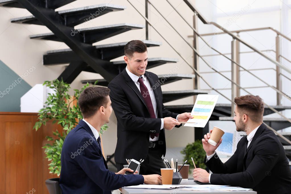 Men in elegant suits having meeting at workplace