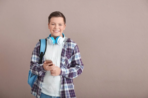 Adolescente con mochila, smartphone y auriculares sobre fondo gris — Foto de Stock