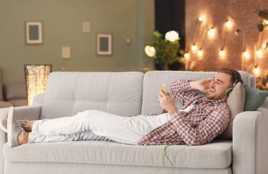Genç adam kanepede evde dinlenirken müzik
