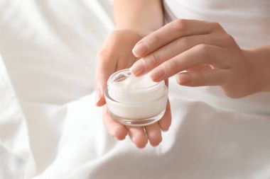 Woman with jar of hand cream at home, closeup clipart