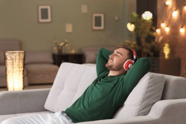 Genç adam kanepede evde dinlenirken müzik