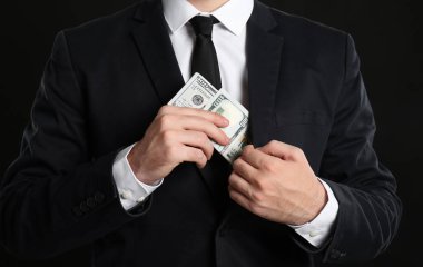İşadamı rüşvet cebinde siyah arka plan üzerine koyarak.
