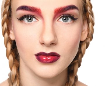 Beyaz arka planda boyalı kaşları olan genç bir kadın, yakın plan.