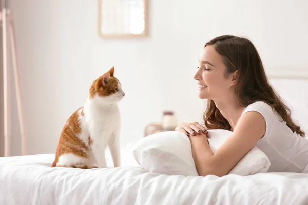 Gyönyörű fiatal nő, aranyos macska ágy otthon — Stock Fotó