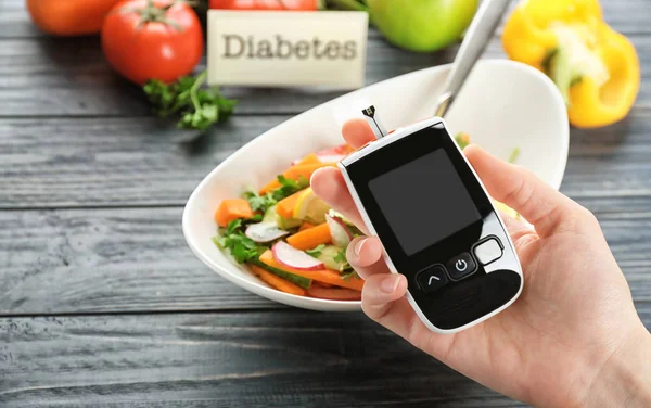 Kobieta Trzyma Cyfrowy Glukometrem Powyżej Tabeli Dieta Cukrzyca — Zdjęcie stockowe