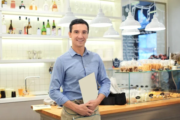 Attractive young waiter at workplace