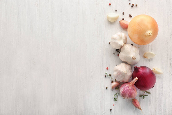Свежий чеснок, лук и перец зерна на светлом фоне, вид сверху
