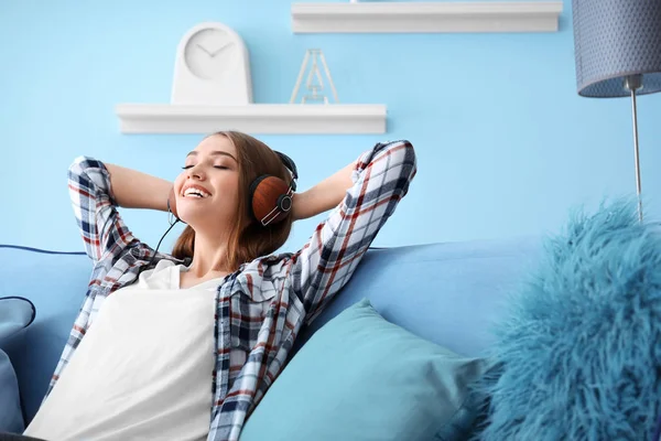 Jovem mulher ouvindo música enquanto relaxa no sofá em casa — Fotografia de Stock