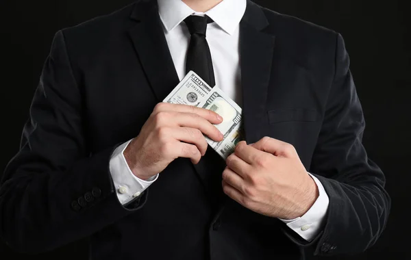 黒い背景にポケットに賄賂を置くビジネスマン — ストック写真