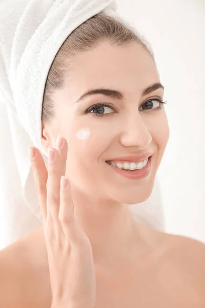 Mujer Joven Aplicando Crema Facial Sobre Fondo Blanco — Foto de Stock