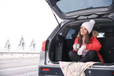 Araba bagajında otururken çay içme kadın turist