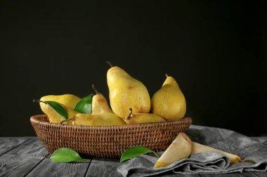 Hasır sepet ile koyu arka plan karşı ahşap masa üzerinde taze olgun armut
