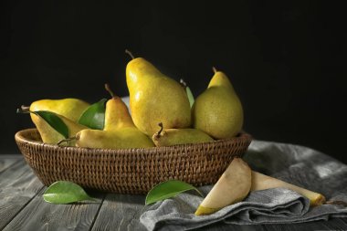 Hasır sepet ile koyu arka plan karşı ahşap masa üzerinde taze olgun armut