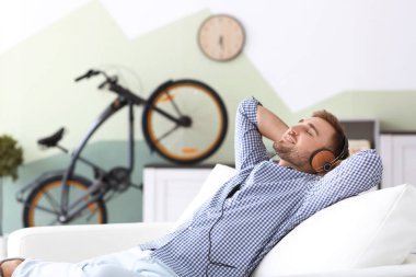 Genç adam kanepede evde dinlenirken müzik