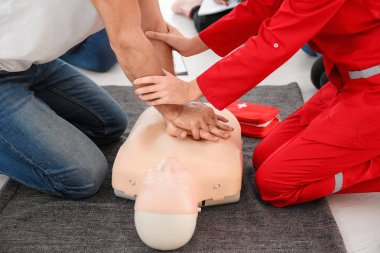 Man practicing CPR on mannequin in first aid class clipart