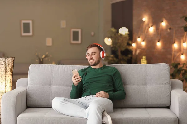 Joven escuchando música mientras se relaja en el sofá en casa —  Fotos de Stock