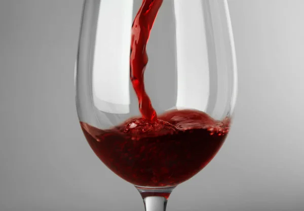 Χύνοντας Κόκκινο Κρασί Ποτήρι Γκρίζο Φόντο — Φωτογραφία Αρχείου